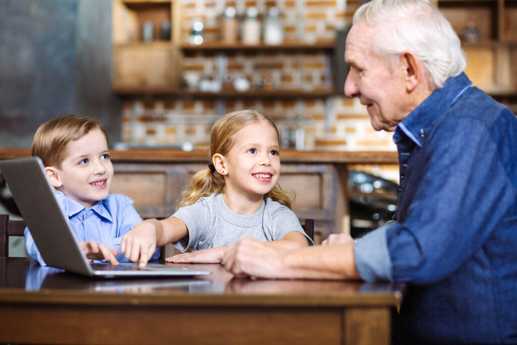 Elderly man using laptop with his grandchildren